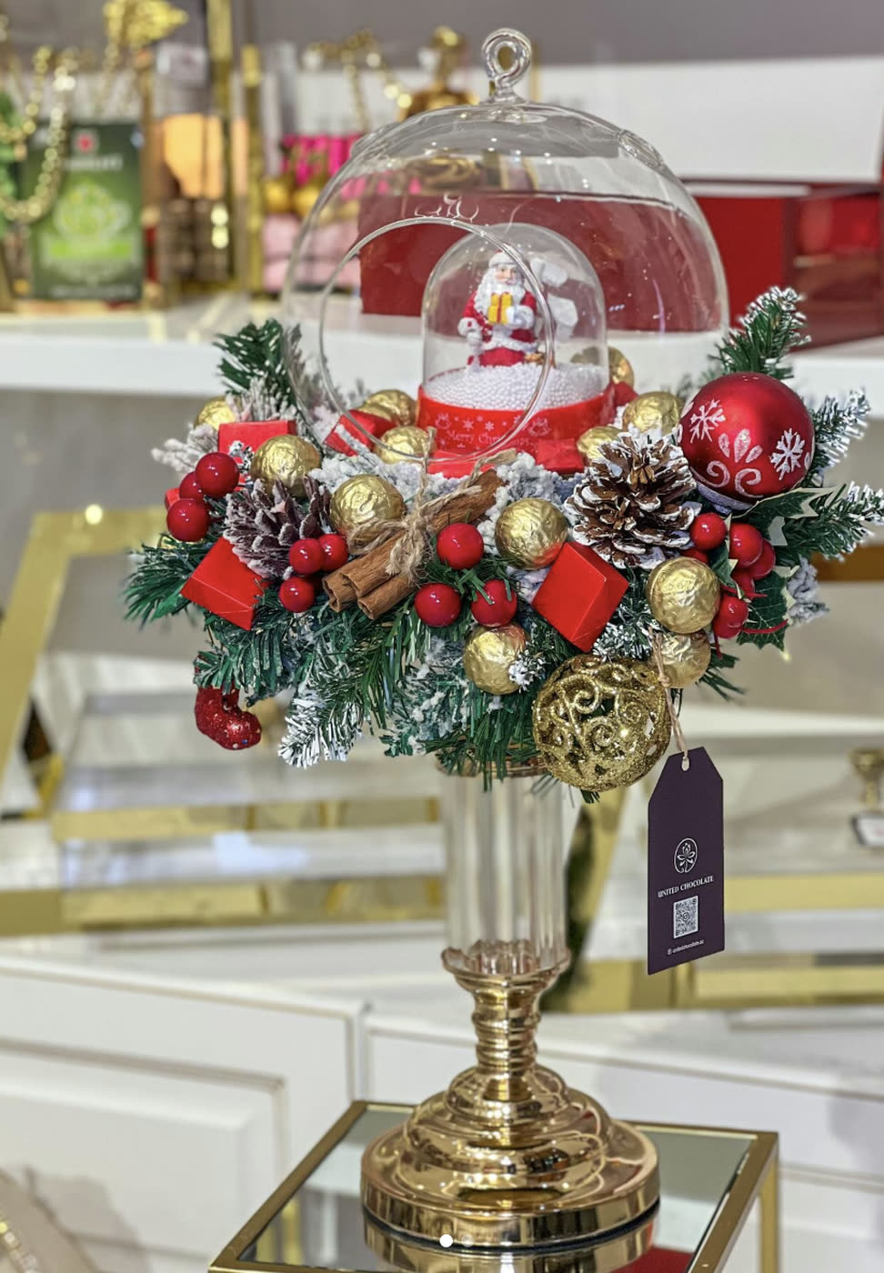 Glass dome with a snowman, red baubles and pine cones on a gold stand